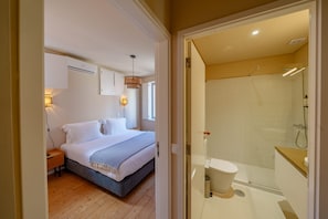 A bedroom with a bed, bedside table, and wall-mounted air conditioning unit.