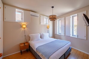 Un dormitorio con cama, lámparas de noche, mesita de noche y ventana con persianas.