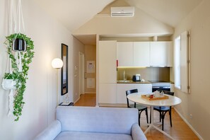 Un apartamento moderno con comedor, kitchenette y sala de estar con sofá.