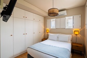 Ein Schlafzimmer mit Bett, Nachttischlampen, einem Kleiderschrank und einem Deckenprojektor.