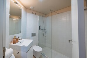 A modern bathroom with a glass-enclosed shower, a white sink, and a mirror.