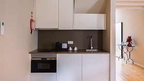 A compact kitchen with a dishwasher, oven, and a coffee maker on the countertop.