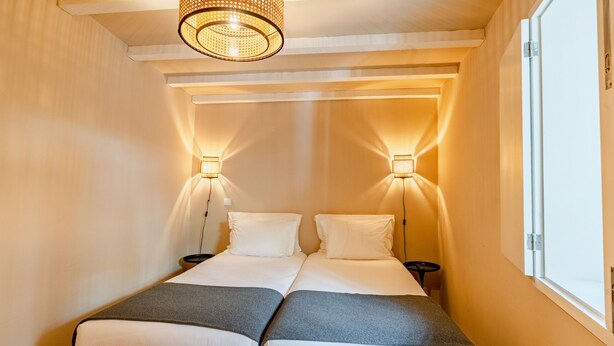 A double bed with two bedside tables, a hanging light fixture, and a window on the right. - Comfortable 1BR Apt for 3 with balcony in Center (Oporto)