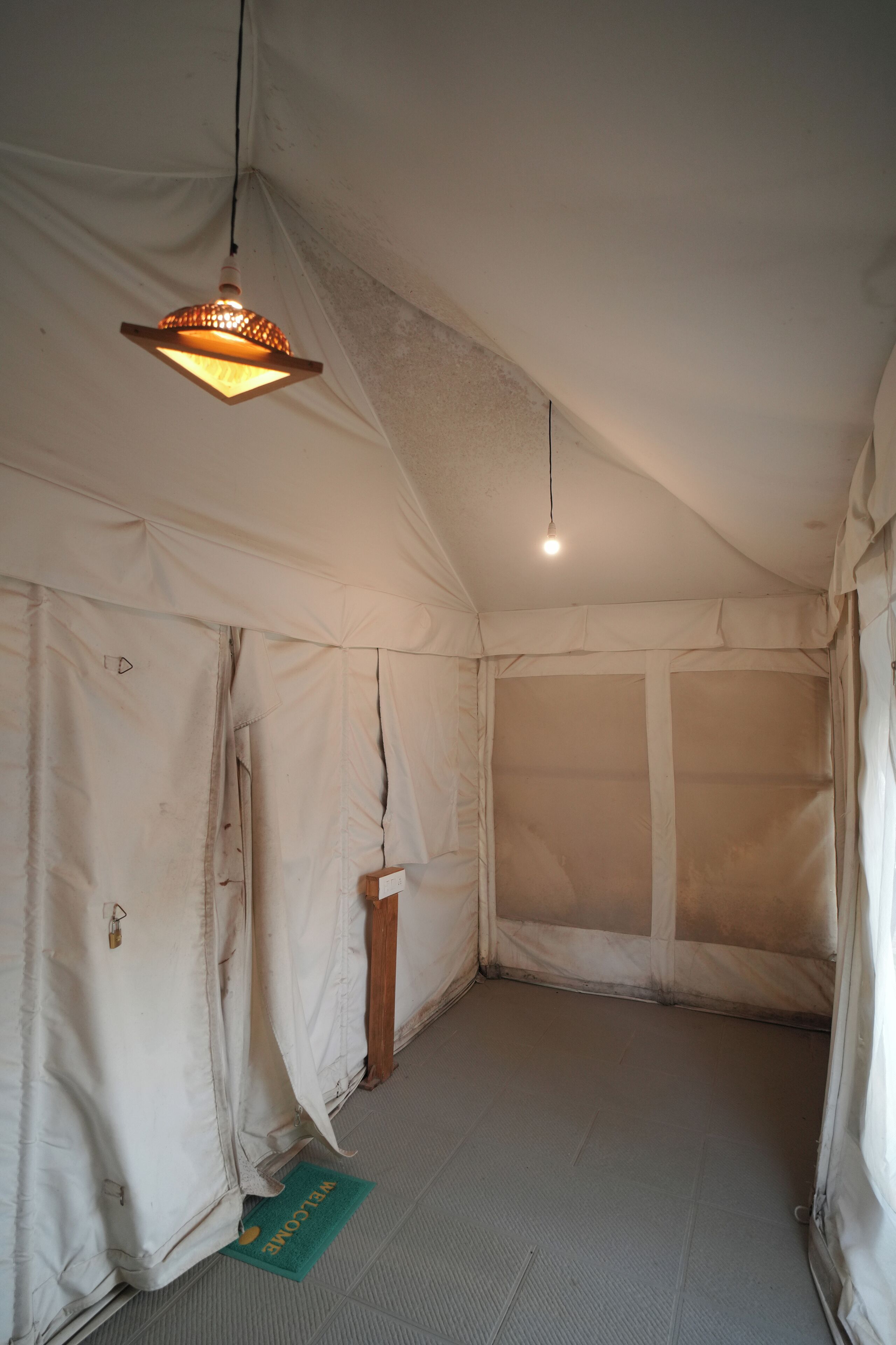 A tent-like room with a hanging light fixture and a door.