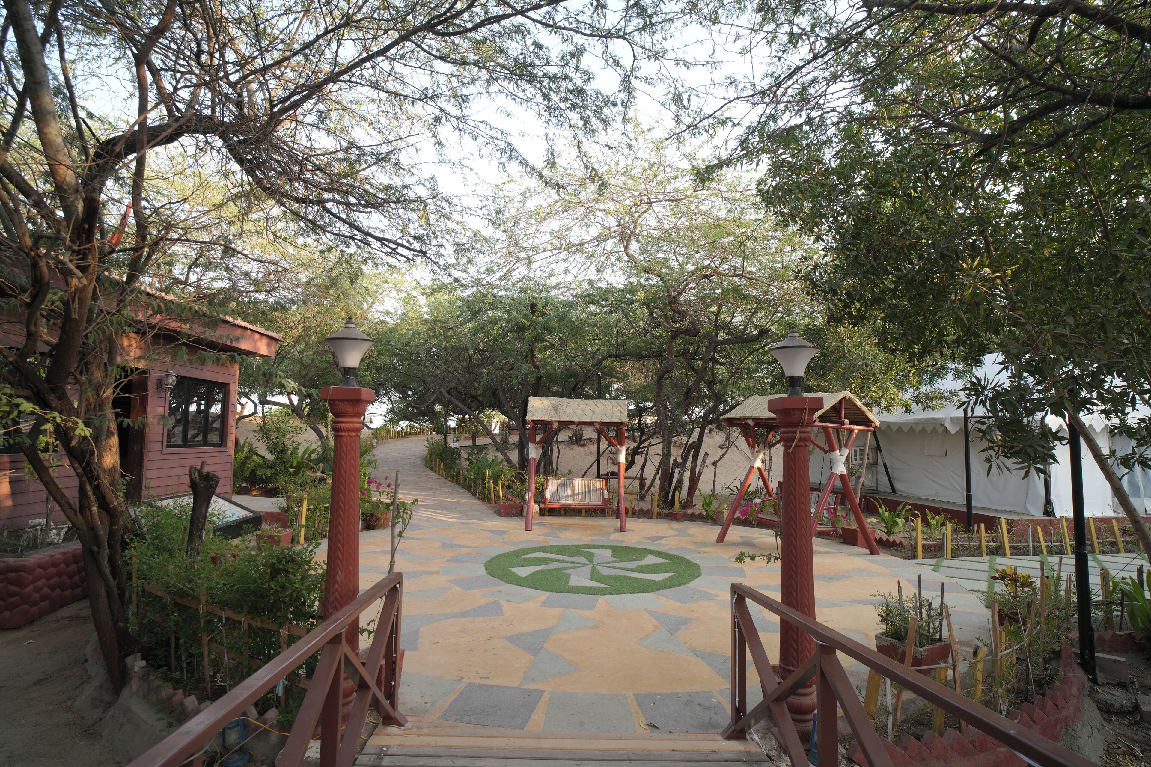 A pathway leading to a gazebo surrounded by trees and potted plants.