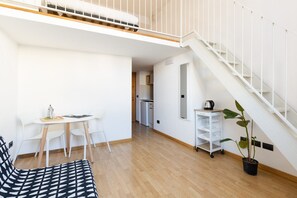 A modern apartment with a dining area, a staircase, and a kitchen in the background.
