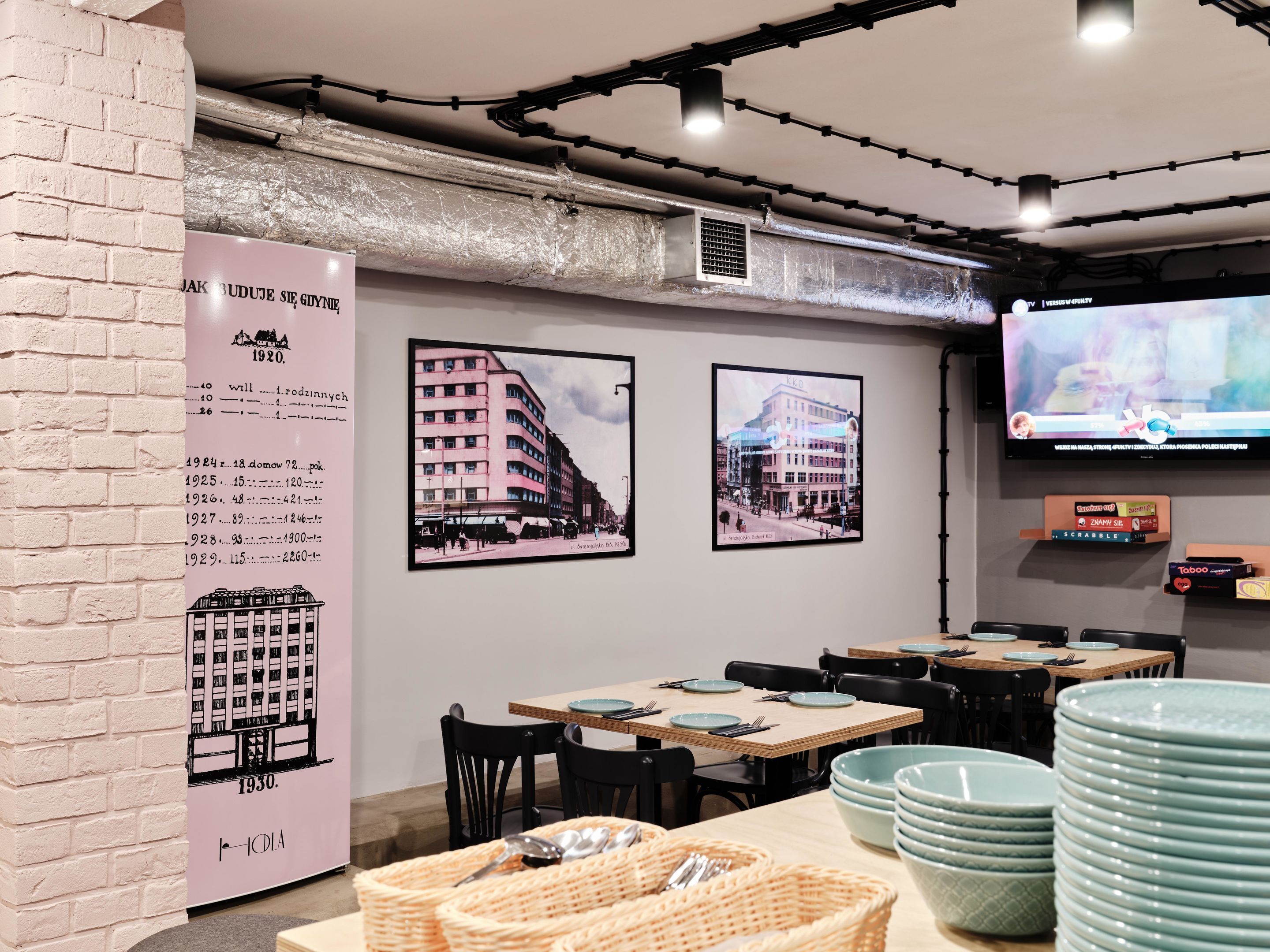A restaurant interior with tables, chairs, a TV, and a wall with historical posters.