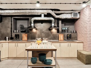 Una cocina moderna con electrodomésticos de acero inoxidable, una isla central con cristalería y una pared de ladrillo decorativa.