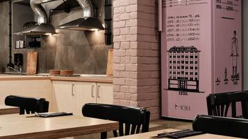 A restaurant interior with brick walls, a large pink menu board, and a modern kitchen with stainless steel appliances.