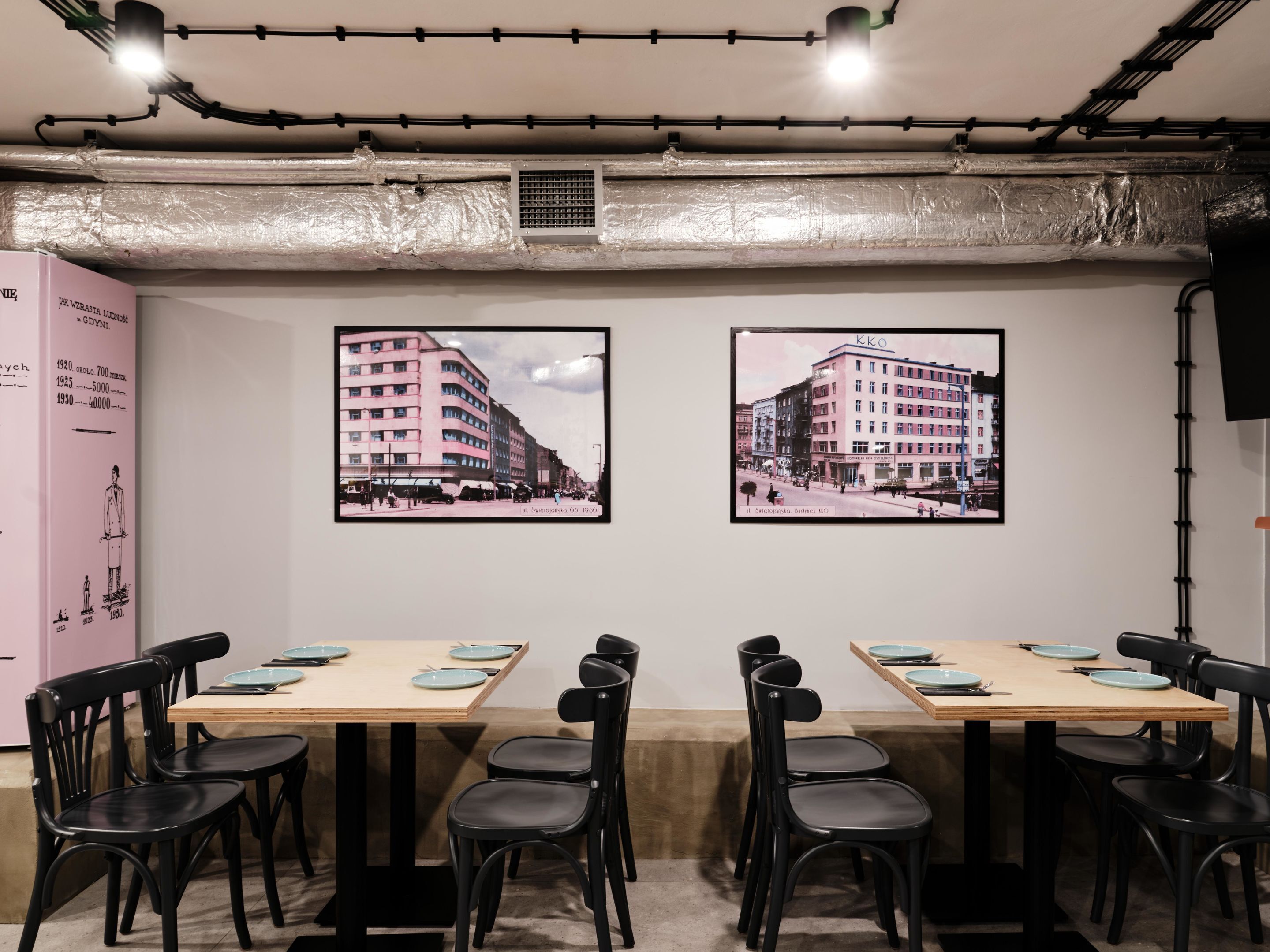 A conference room with two framed photographs of buildings, a pink cabinet with text, and a table set for six with black chairs.