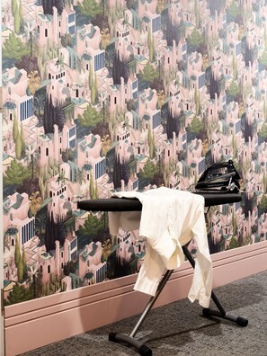 A room with a patterned wallpaper, a black ironing board, and a white shirt on it. - Hola Gdynia (Gdynia)