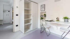 A modern kitchen with white cabinetry, a bar area, and a dining space. - GuestHost - APT overlooking quiet inner courtyard! (Milano)