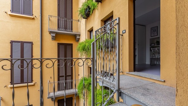 A multi-story building with balconies, a metal gate, and a staircase. - GuestHost - APT overlooking quiet inner courtyard! (Milano)