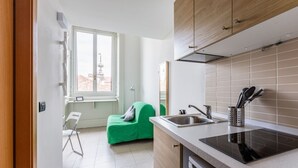 A modern kitchen with a built-in stove, a sink, and a window overlooking a cityscape.