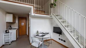 A compact living space with a kitchen, dining area, and a staircase.