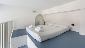 A modern hotel room with a large bed, a bedside table, and a small nightstand.