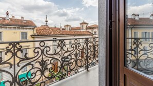 Un balcón con barandillas de hierro forjado con vistas a un paisaje urbano de tejados de tejas rojas y edificios de colores pastel.