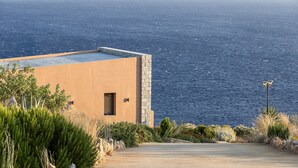A coastal building with a stone facade, a flat roof, and a view of the sea.