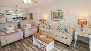 A living room with a sofa, armchairs, a coffee table, and a ceiling fan.