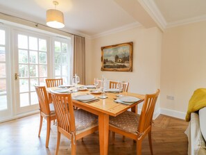 A dining room with a wooden table set for six, six chairs, and a painting on the wall. - 7 The Green (Lichfield)