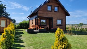 A wooden cabin with a porch, two windows, and a satellite dish.