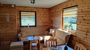 A cozy cabin interior with a wooden interior, a sofa, a dining table, and a small window.