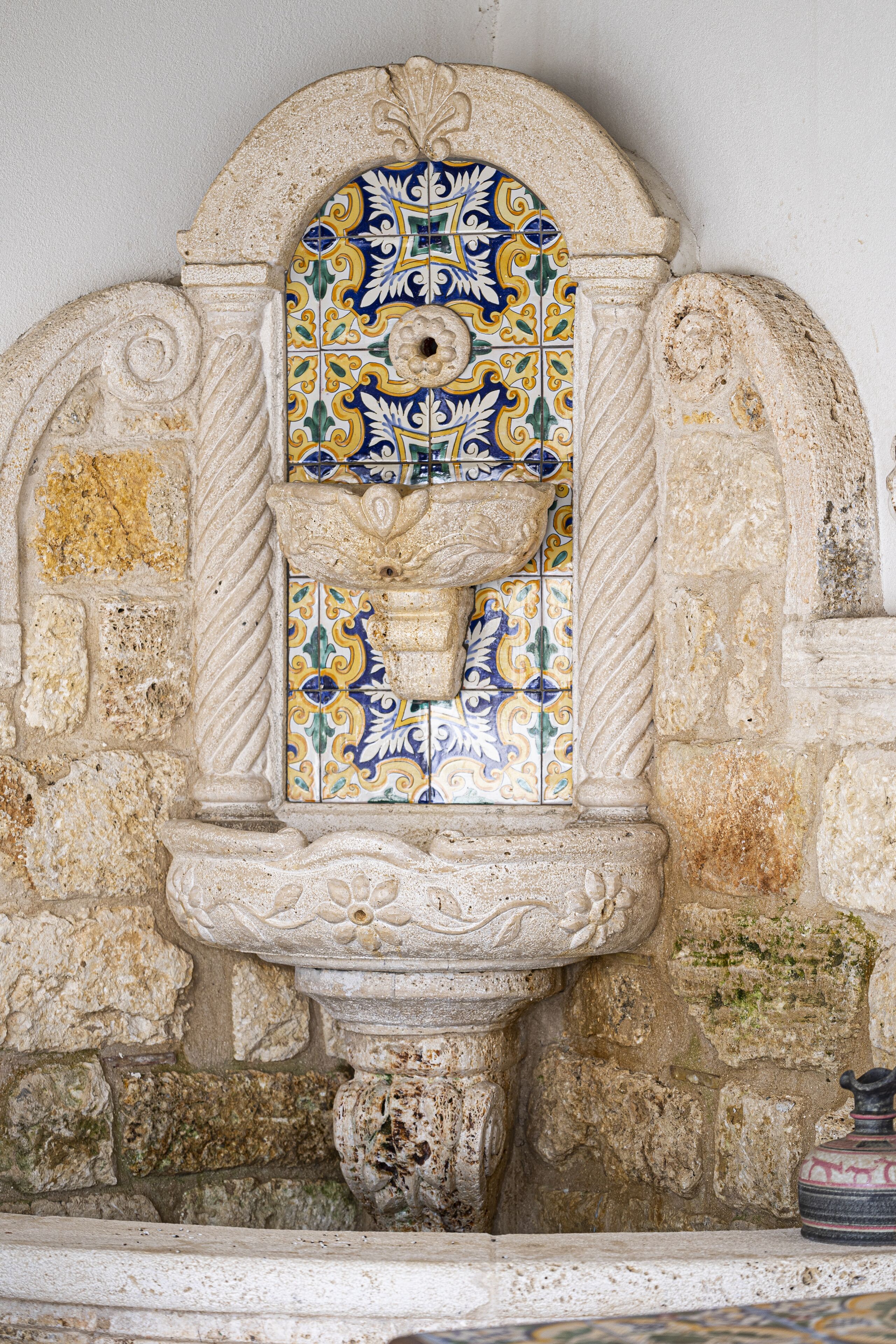 A stone wall with a decorative tile archway.