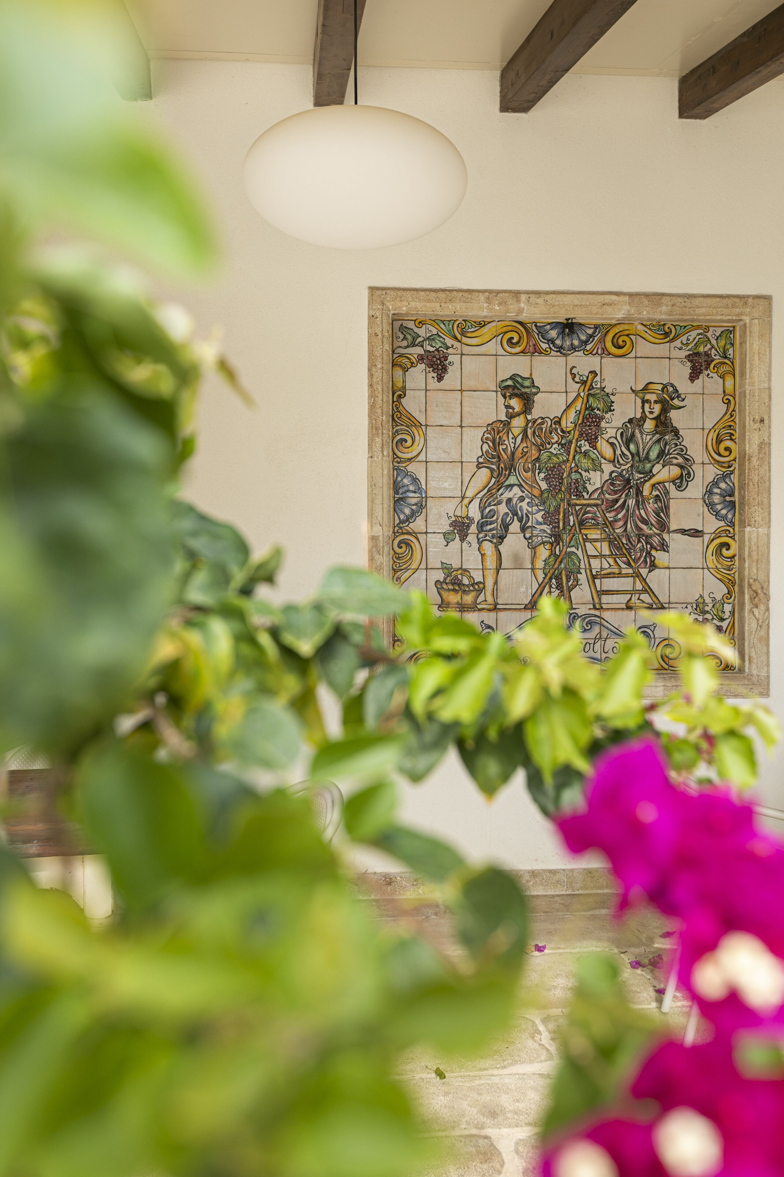 A tiled wall with a mosaic depicting figures and grapes.