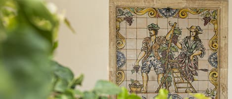 A tiled wall with a mosaic depicting figures and grapes.