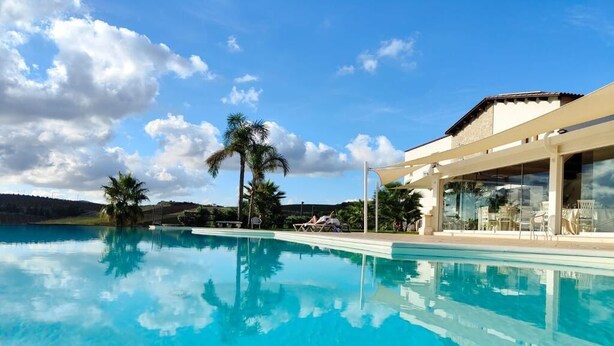 Una piscina azul cristalina con vistas a un edificio y palmeras al fondo.