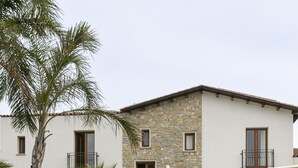Un edificio con fachada de piedra, una escalera exterior y una palmera.