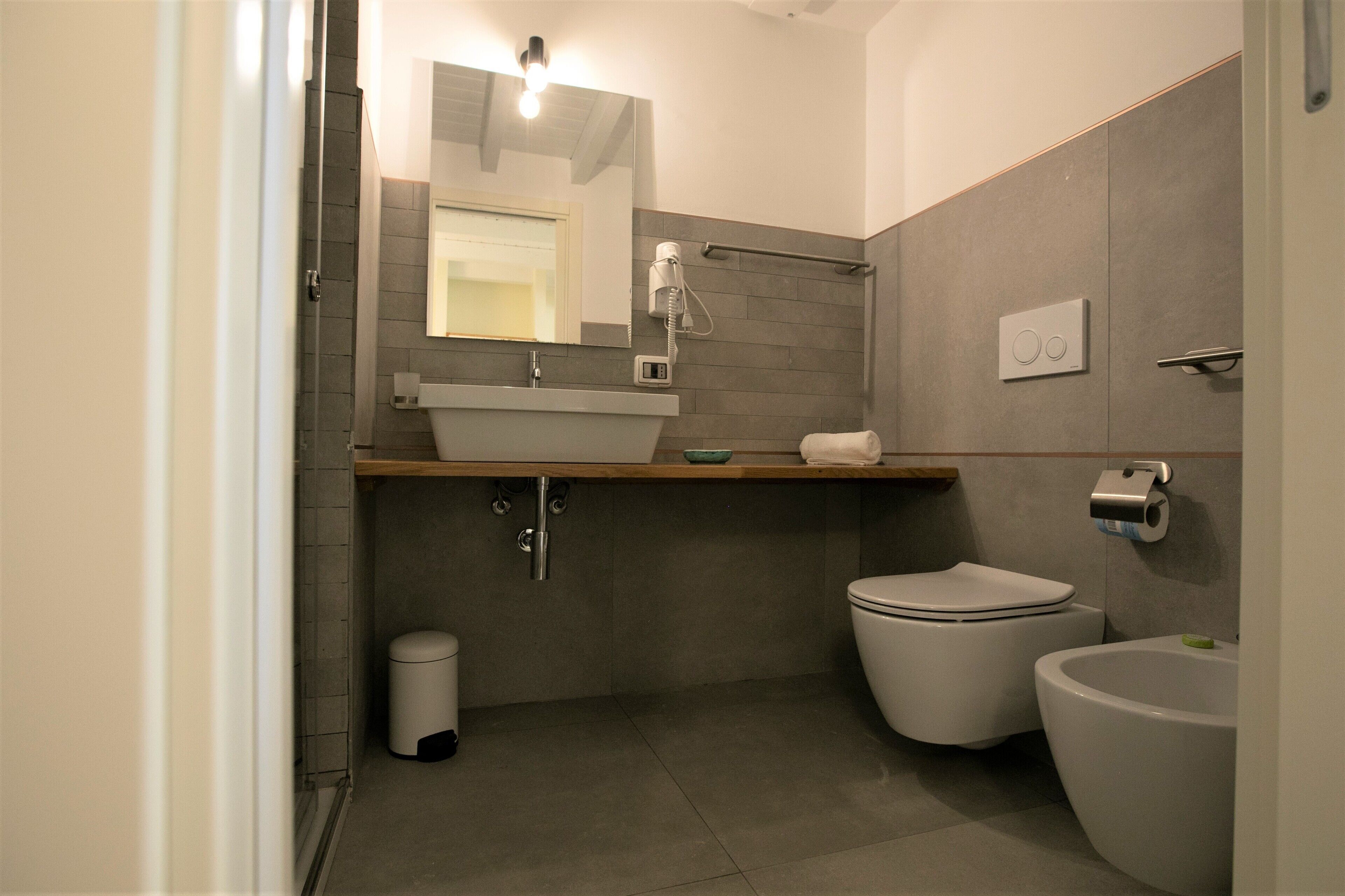 Un bagno moderno con lavandino, vaso, bidet e specchio.