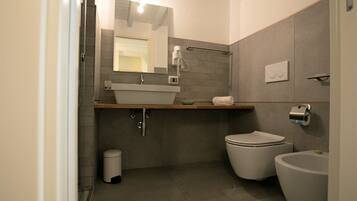 Un bagno moderno con lavandino, vaso, bidet e specchio.