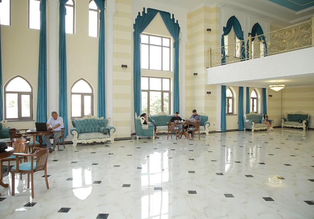 A spacious lobby with high ceilings, large windows, and a polished marble floor.