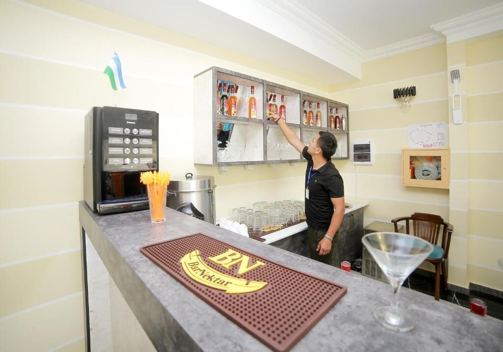 A bar area with a minibar, a coffee machine, and a bartender.