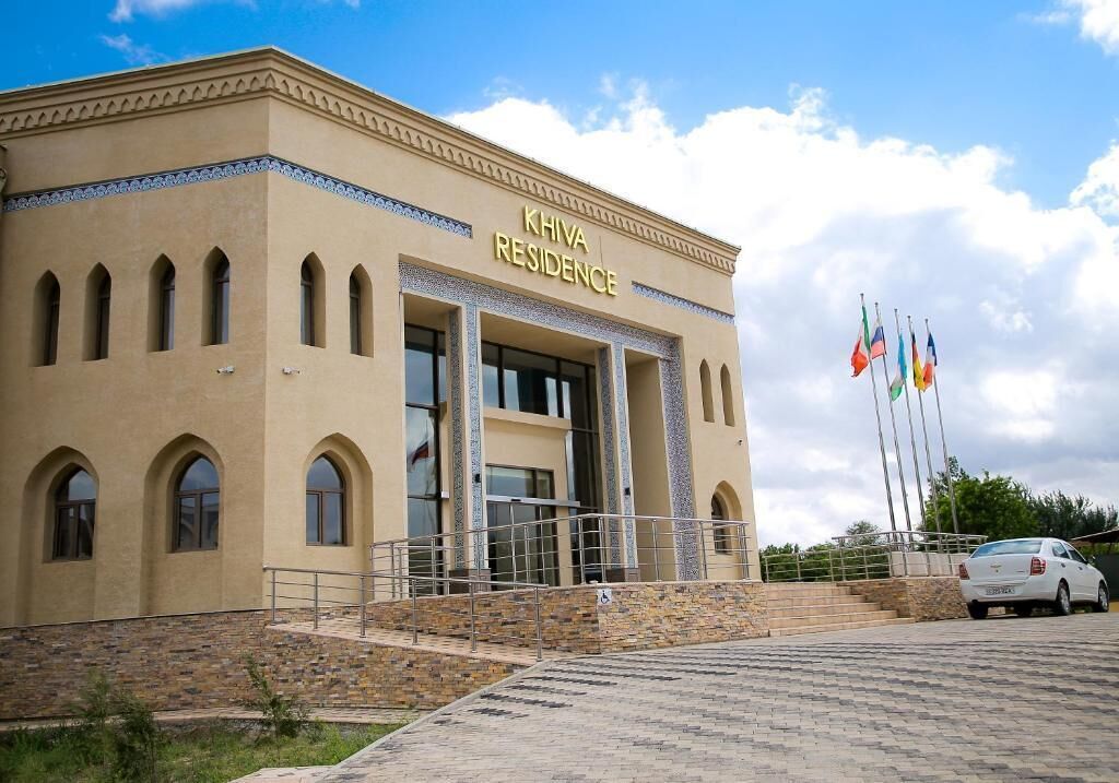 A building labeled "KHIVA RESIDENCE" with a stone facade, arched windows, and a central entrance.