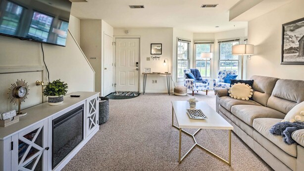 A living room with a TV mounted on the wall, a sofa, a coffee table, and a staircase leading to another room. - Historic Dtwn Home: 2 Mi to Military Park! (Gettysburg)