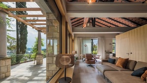 A spacious living area with a stone column, a wooden ceiling, and a view of the outdoors. - Vila Laguna Strunjan (Piran)