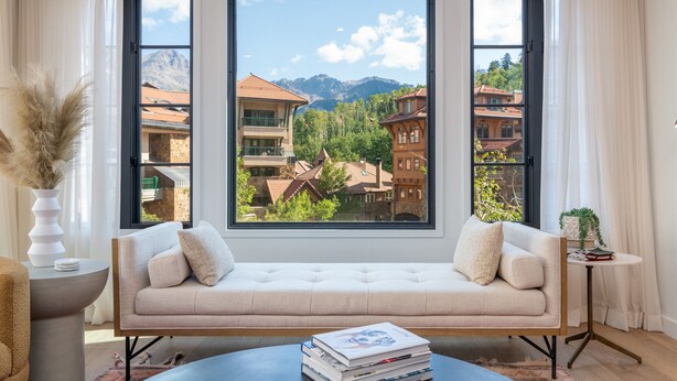 A modern living room with a large window, a beige sofa, a round coffee table with books, and a vase with pampas grass. - Exceptional Residence by InvitedHome | Mountain Village Core, Family Friendly (Mountain Village)