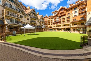 A courtyard with green artificial turf, a white tent, and multi-story buildings with balconies. - Exceptional Residence by InvitedHome | Mountain Village Core, Family Friendly (Mountain Village)
