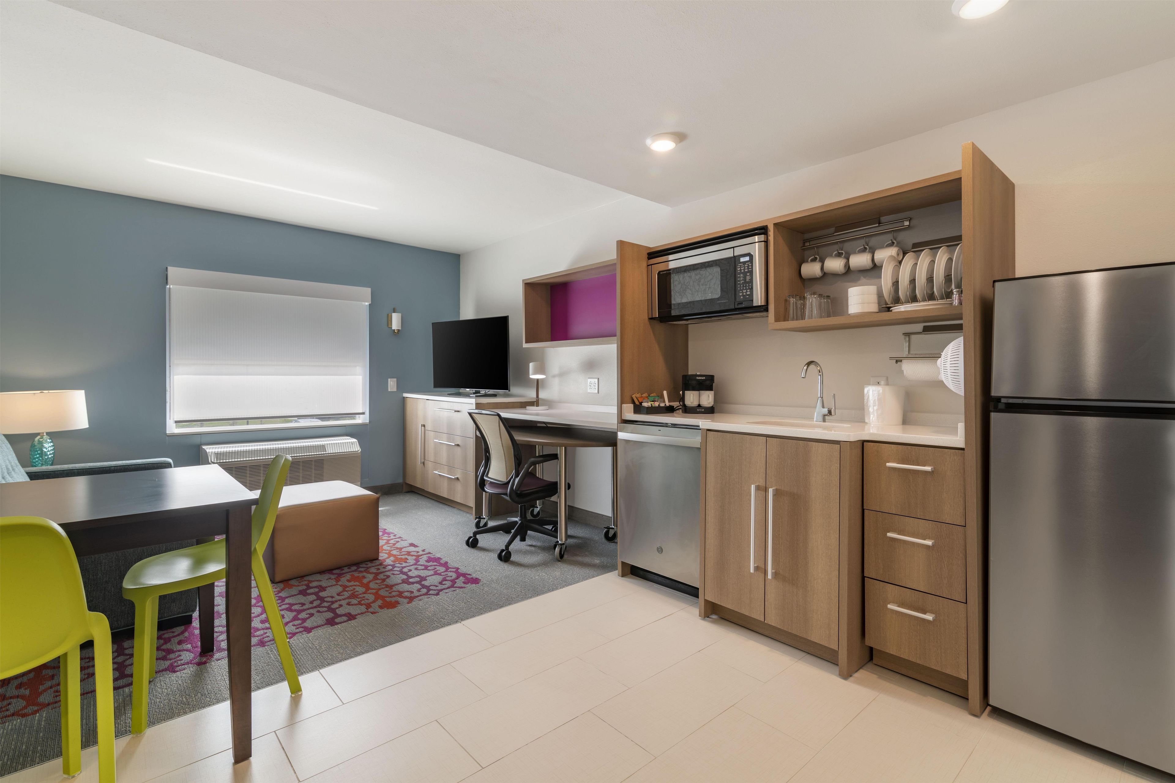 A modern kitchen with a built-in microwave, stainless steel refrigerator, and wooden cabinets.