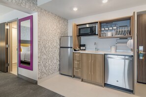 A compact kitchen with a refrigerator, microwave, and built-in oven. - Home2 Suites by Hilton Bangor (Bangor)