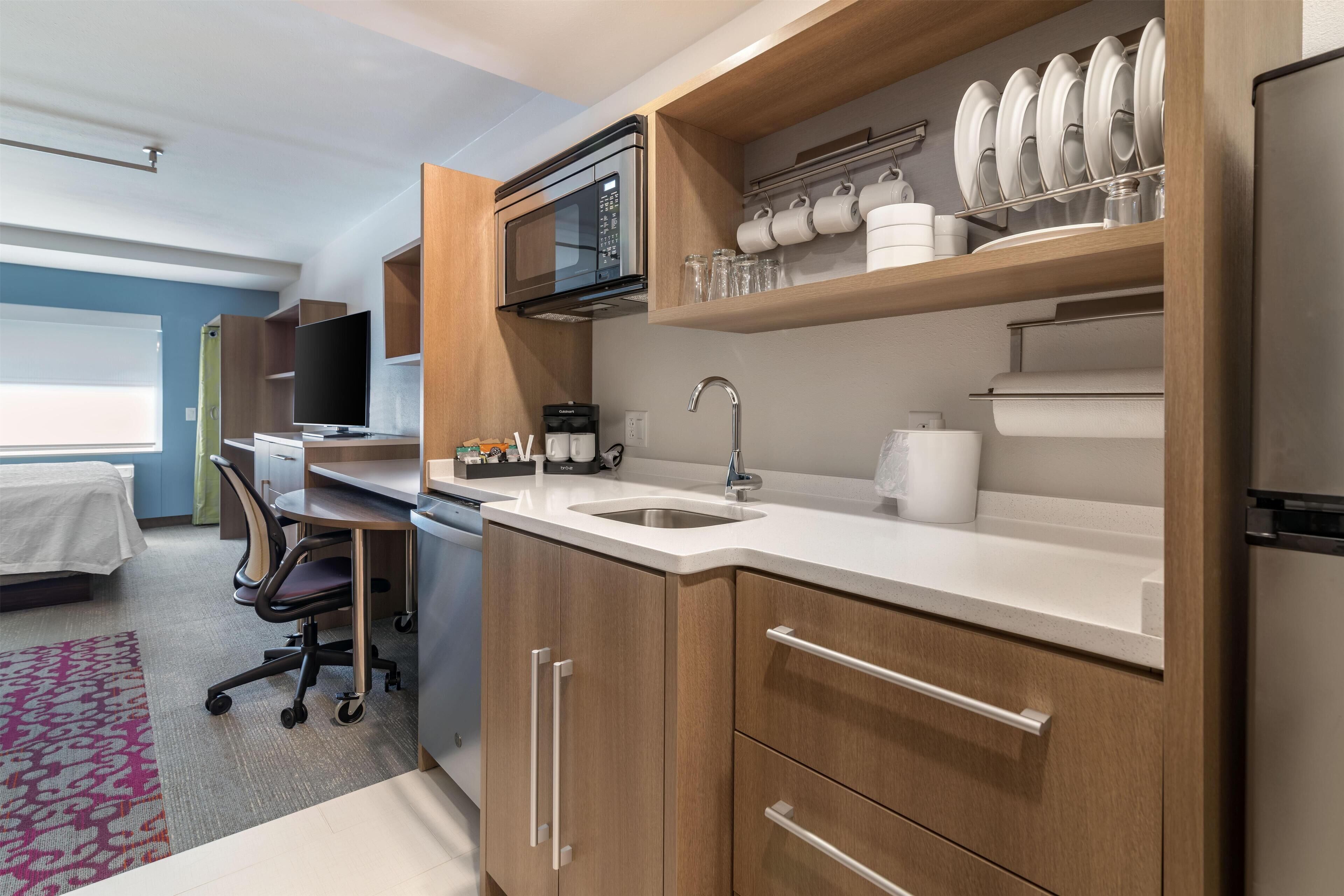 Een moderne keuken met houten kastjes, een roestvrijstalen koelkast, een magnetron en een koffiezetapparaat.