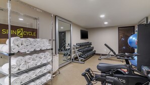 Een sportschool met trainingsapparatuur, handdoeken en een spiegel.