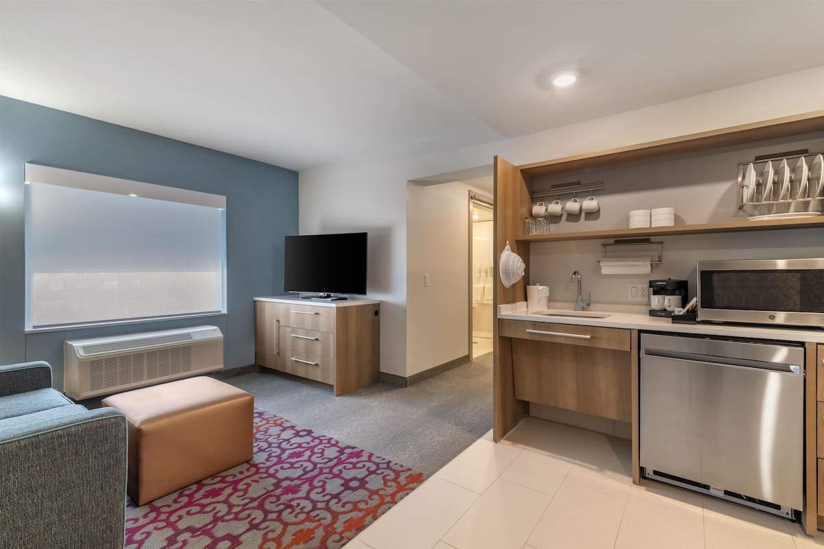 A modern kitchen with a built-in microwave, stainless steel appliances, and a flat-screen TV.