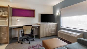 Una habitación de hotel moderna con escritorio, silla, televisión y un ventanal grande.