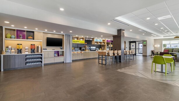 Een moderne hotellobby met een bar, zitplaatsen en een televisietoestel.