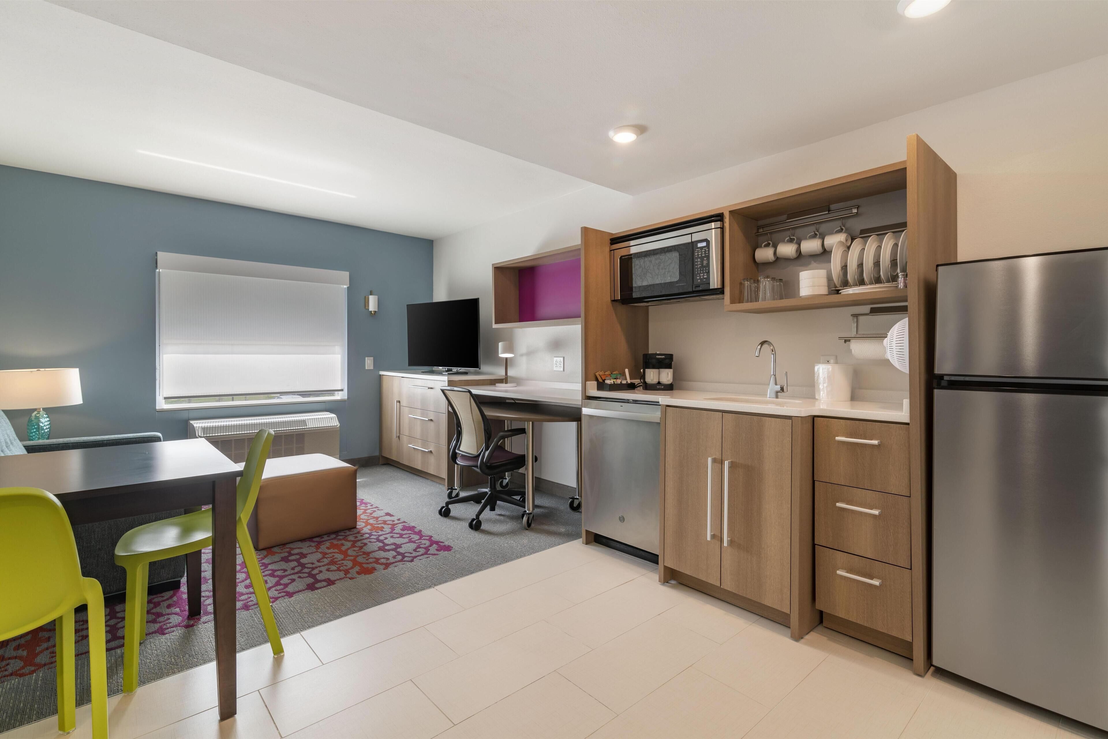 A modern kitchen with a built-in microwave, stainless steel refrigerator, and wooden cabinets.