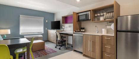 A modern kitchen with a built-in microwave, stainless steel refrigerator, and wooden cabinets.