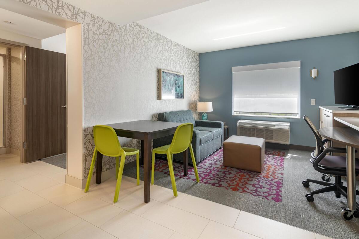 A modern room with a dining area, a sofa, a TV, and a desk.